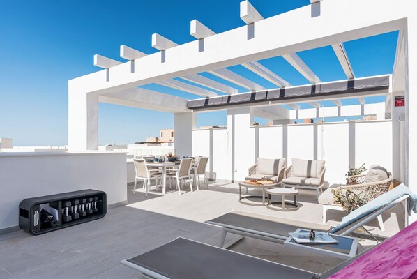 Une terrasse sur le toit comprenant un espace repas, des sièges et une prise de courant.