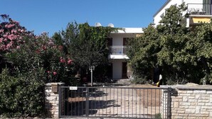 A residential building with a gated entrance, a balcony on the upper floor, and surrounding greenery. - Beach apartment Srima (Vodice)