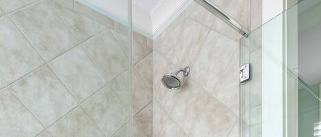 A glass-enclosed shower with beige tiles and a visible showerhead.