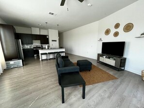 A modern living room with a sectional sofa, a coffee table, and a flat-screen TV on a wooden TV stand.