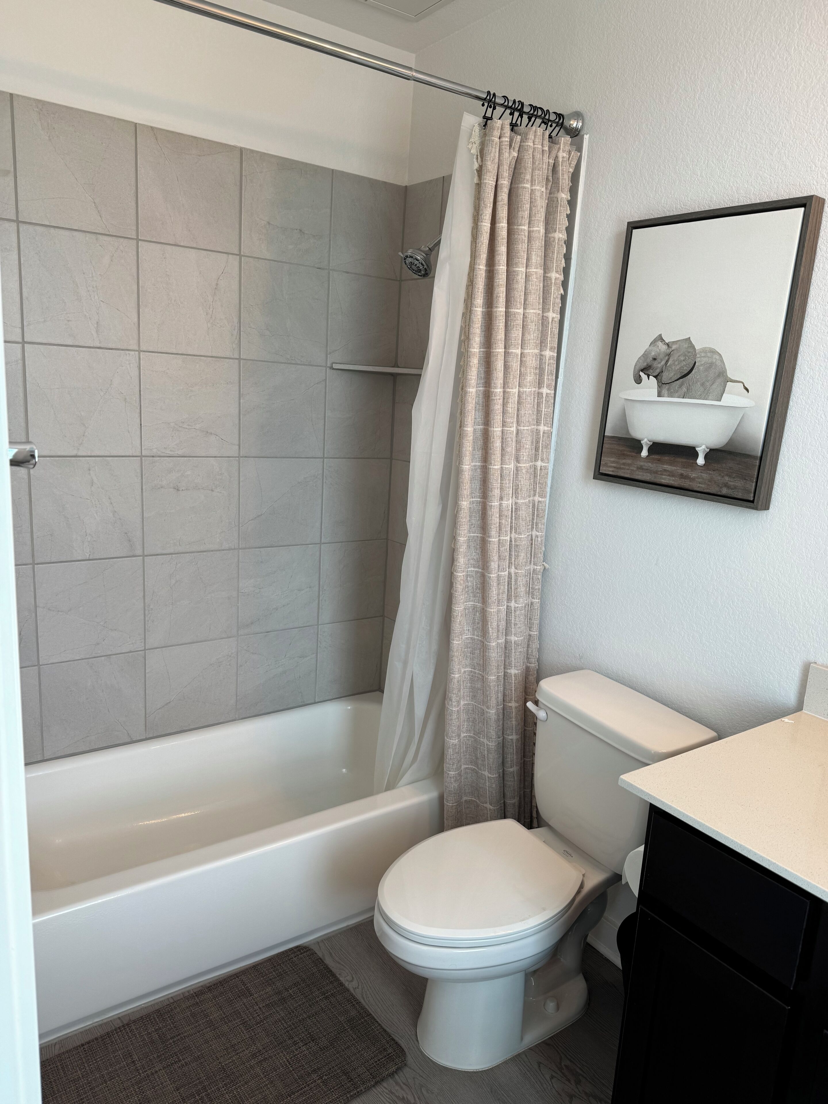 A bathroom with a bathtub, toilet, and a shower curtain.