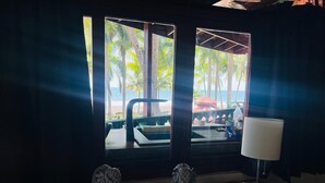 Ein Zimmer mit Blick auf einen Strand, eine Couch, eine Lampe und zwei dekorative Statuen.
