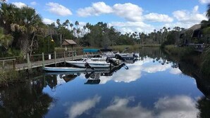 Un cos d'aigua serena amb barques amarrades, envoltat de verdura i un cel clar.