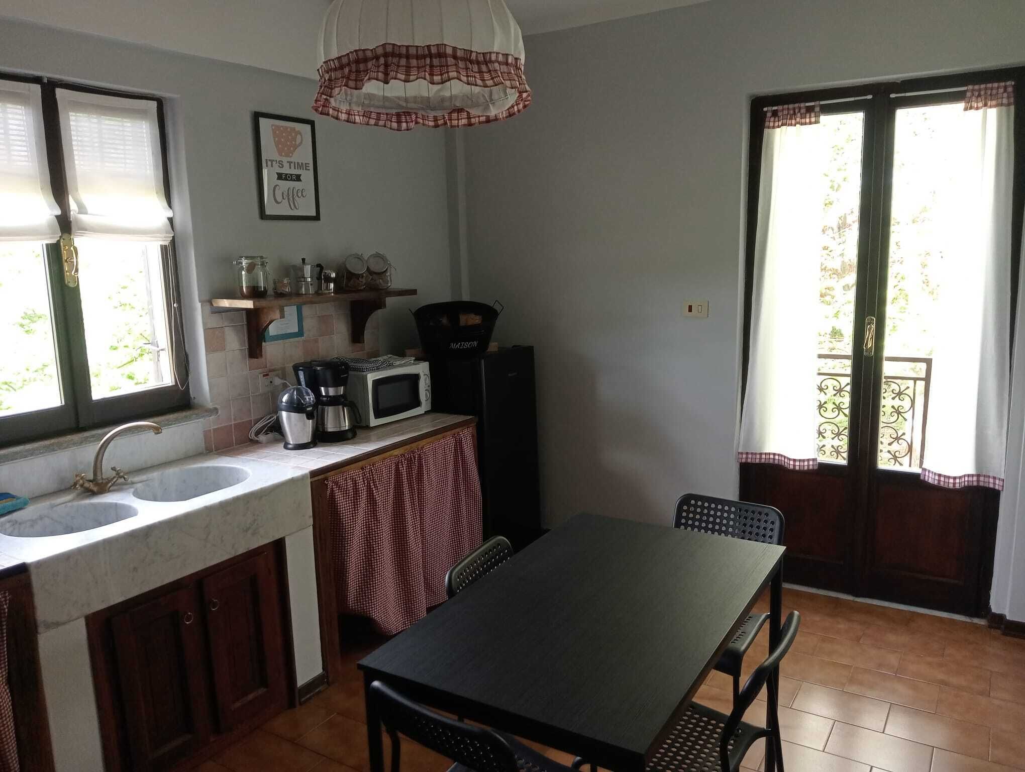 A compact kitchen with a sink, microwave, coffee maker, and a dining table with chairs.