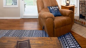 A cozy living room with a leather armchair, a wooden coffee table, and a fireplace.