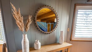 A wooden console table with a round mirror, two white vases, and dried plants against a paneled wall. - Yosemite Chalet, Golf Course Views, Game Room, Walk to Lake, Sleeps 12 (Groveland)