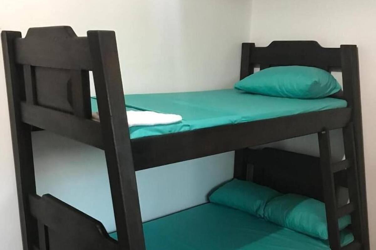 Una litera con ropa de cama verde y una almohada blanca.