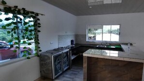 Une cuisine compacte dotée d’un îlot central, d’une cuisinière intégrée et d’une fenêtre donnant sur l’extérieur.