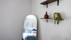 A bedroom with a bed, a mirror, a shelf with decorative items, and a wall-mounted shelf with a plant. - Cozy den in Columbus (Columbus)
