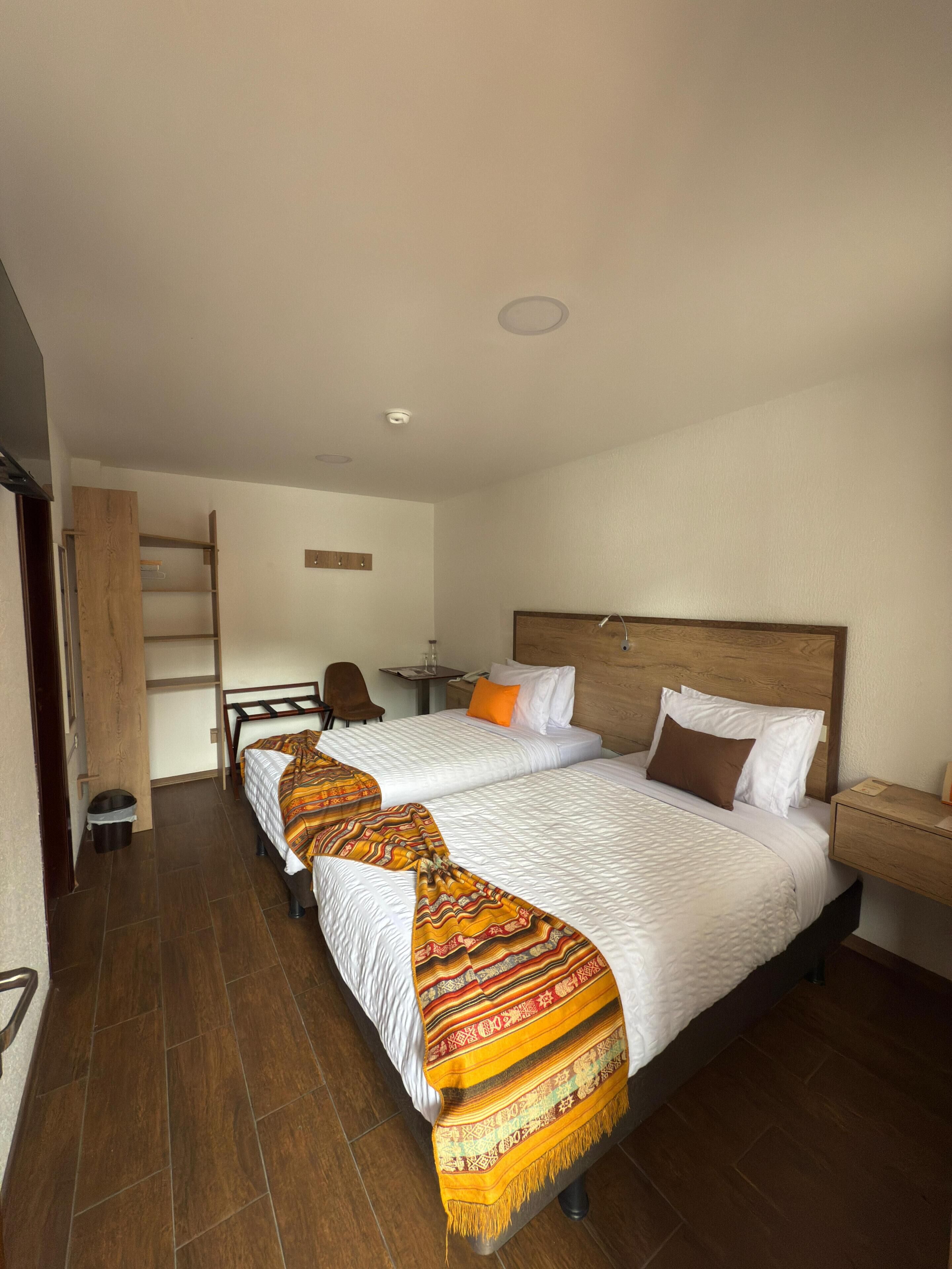 Une chambre d’hôtel avec deux lits, un bureau, une chaise et une petite table.