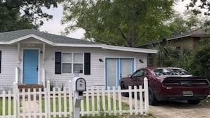 Une maison mobile de plain-pied avec une porte d’entrée bleue, une boîte aux lettres et une clôture blanche en piquets.