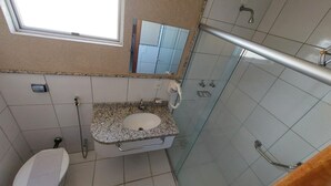 Ein Badezimmer mit Fenster, Waschbecken, Toilette und Duschbereich.