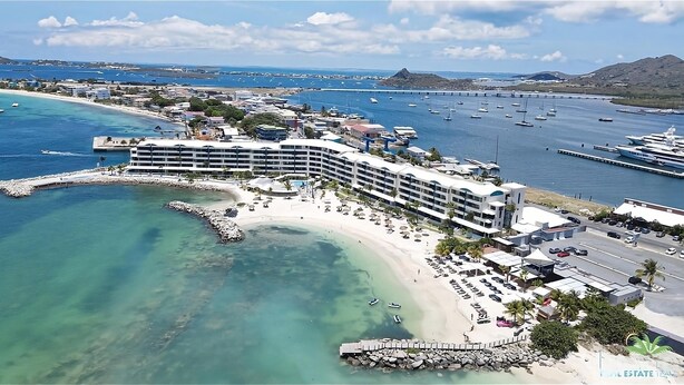 Un hôtel situé sur la côte, avec accès direct à la plage, plusieurs piscines et un port de plaisance avec des bateaux.