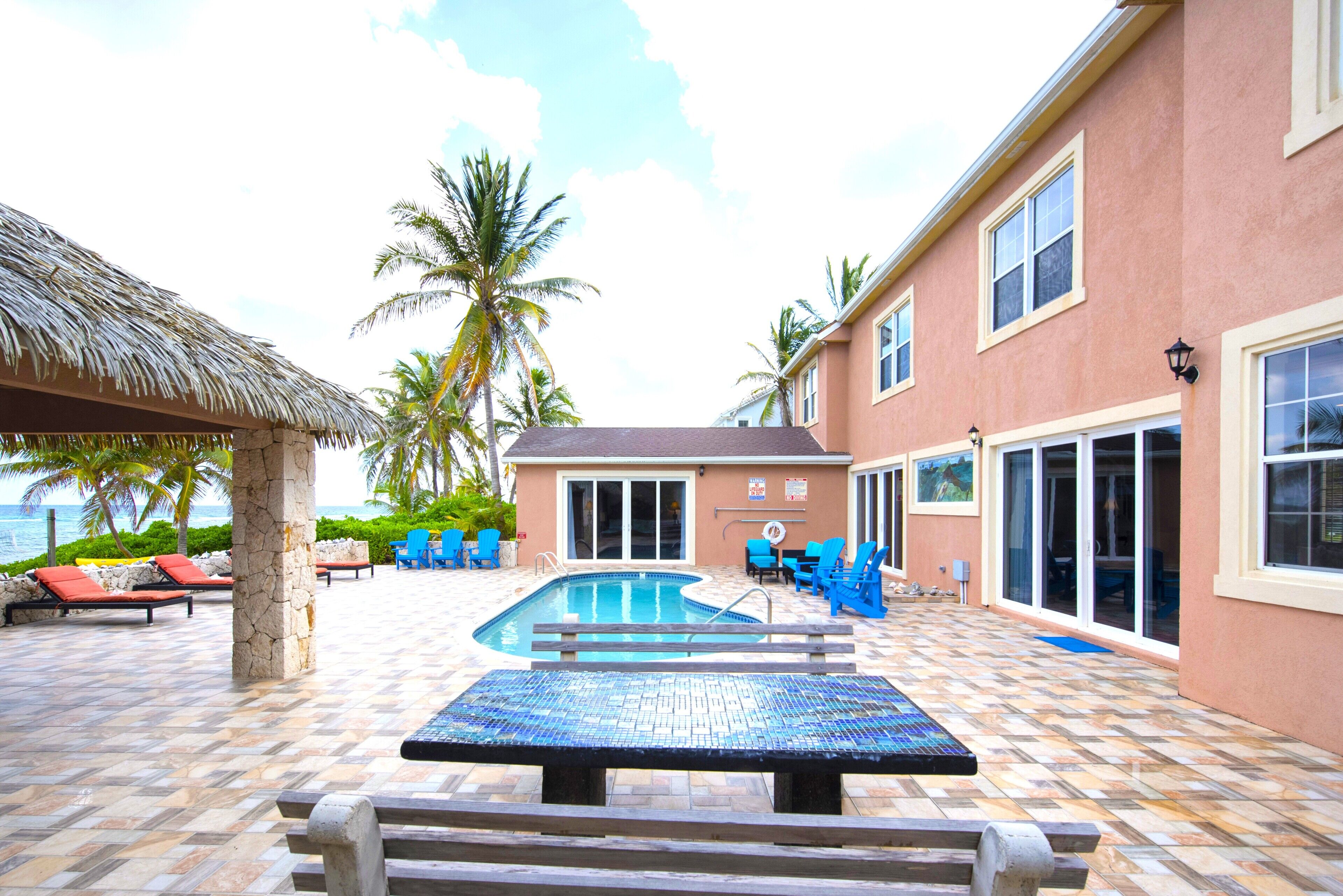 A swimming pool area with lounge chairs and a thatched roof structure.