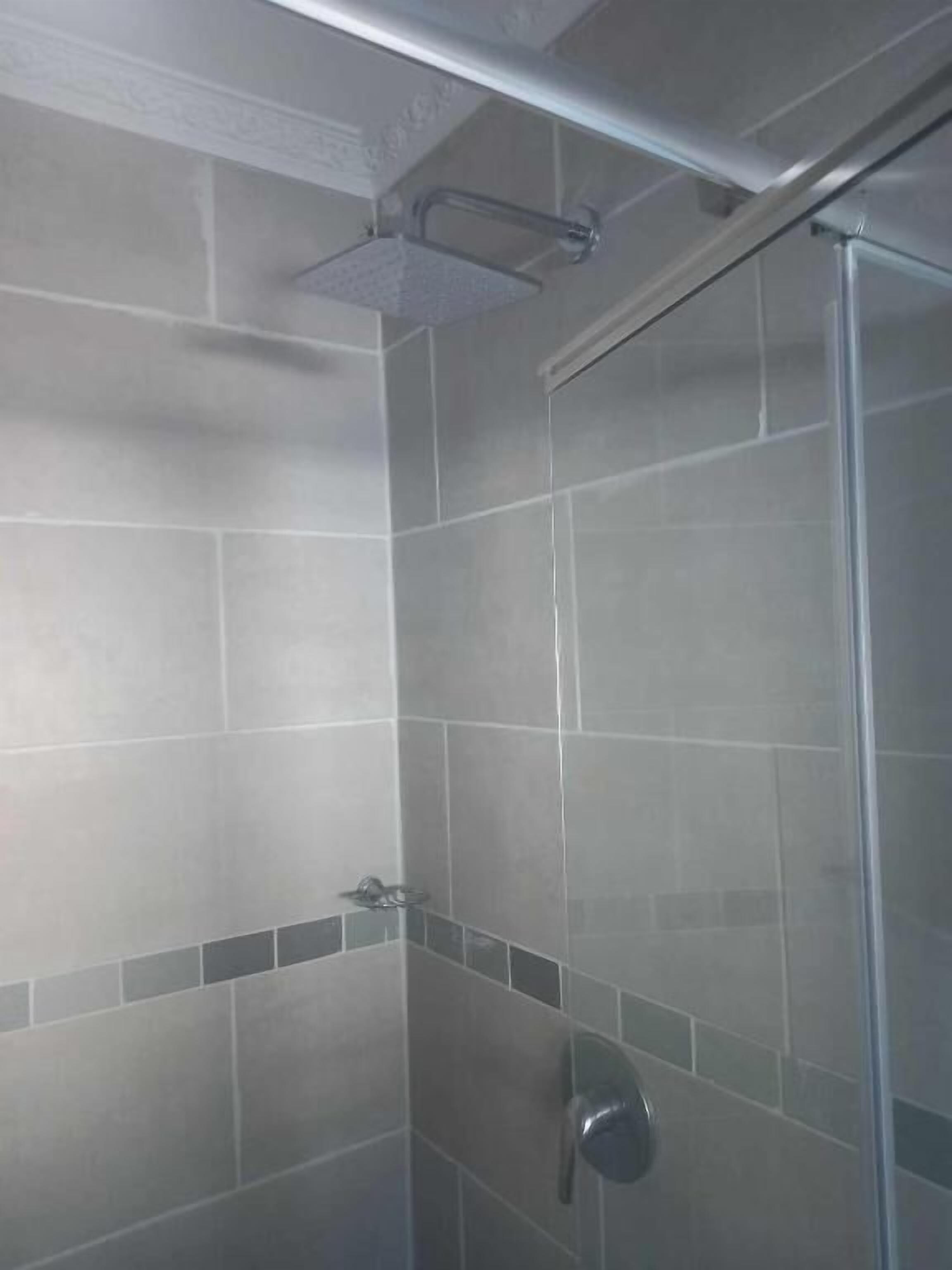 A shower with a glass door, tiled walls, and a metal towel rack.