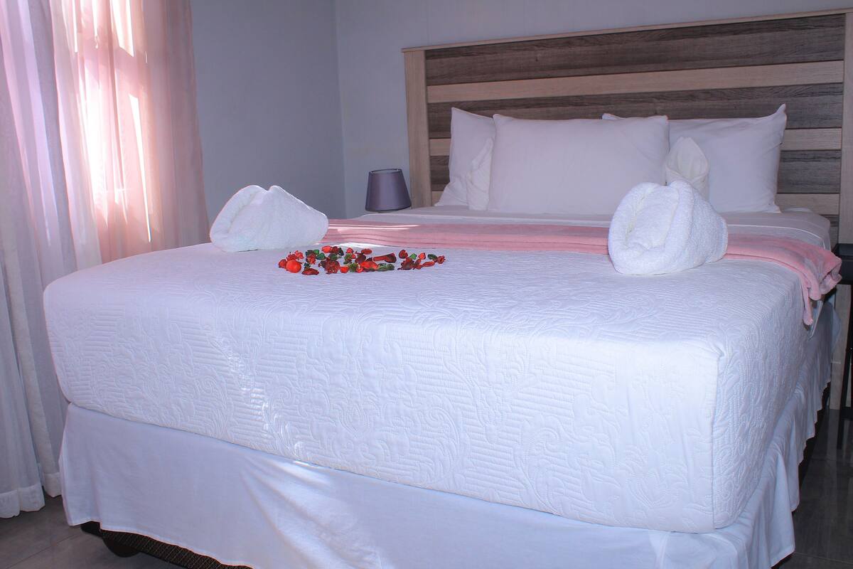 A neatly made bed with white linens and two towels placed on the bed.