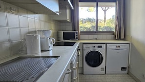 Une cuisine compacte équipée d’un lave-linge, d’un four à micro-ondes et d’une machine à café.