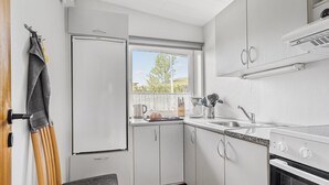 A compact kitchen with a built-in oven, a sink, and a window providing natural light.