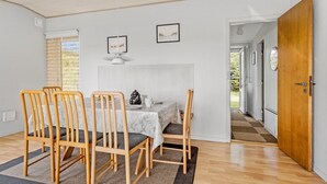 A dining area with a table set for four, wooden chairs, a marble tablecloth, and two framed pictures on the wall.
