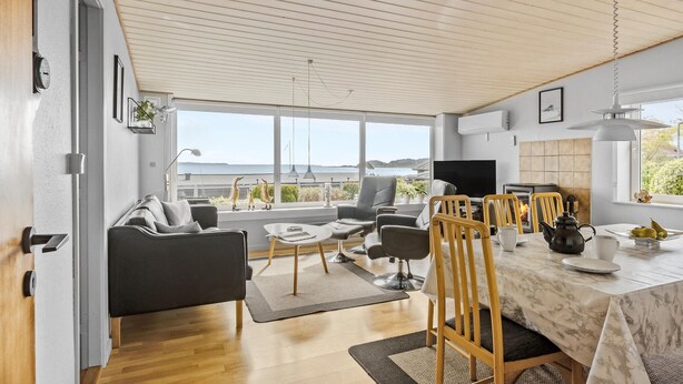 A spacious living area with a large window overlooking a scenic view, a dining table with chairs, and a comfortable seating arrangement.