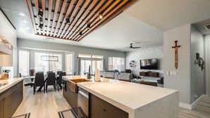 A modern kitchen with a large island, dining area, and a living space with a TV. - Modern Luxury! Only 10 min. to AZ Athletic Grounds & A+ Dining Shopping! (Mesa)