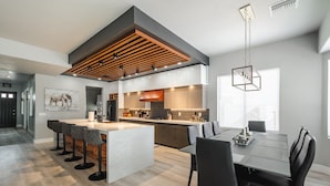 A modern kitchen with a central island, bar stools, and a dining area with a table and chairs. - Modern Luxury! Only 10 min. to AZ Athletic Grounds & A+ Dining Shopping! (Mesa)