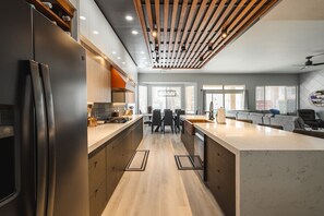 A modern kitchen with a central island, wooden ceiling beams, and a dining area with a view of the city. - Modern Luxury! Only 10 min. to AZ Athletic Grounds & A+ Dining Shopping! (Mesa)