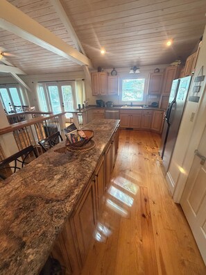 A kitchen with wooden cabinets, a granite countertop, and a stainless steel refrigerator.