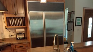 A kitchen with wooden cabinets, a stainless steel refrigerator, a sink, and a countertop. - Spacious home with EV charging station two miles from Big Bay Town Park. (La Pointe)