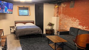 Ein modernes Zimmer mit einem Bett, einer Couch, einem kleinen Tisch und einem an der Wand befestigten Fernseher.