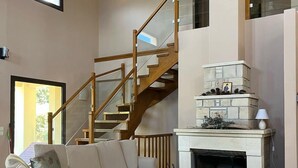 A living room with a beige sofa, a wooden staircase, and a fireplace.