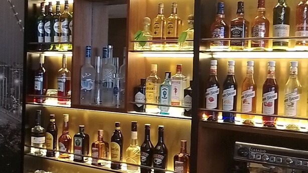A well-lit bar area with multiple shelves of various liquor bottles. - Ramisac Hospitality  (Lekki)