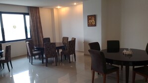 A conference room with a large table and multiple chairs, a window with curtains, and a wall-mounted artwork. - Ramisac Hospitality  (Lekki)