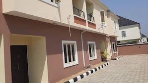 A multi-story residential building with a paved driveway and a balcony on the second floor. - Ramisac Hospitality  (Lekki)