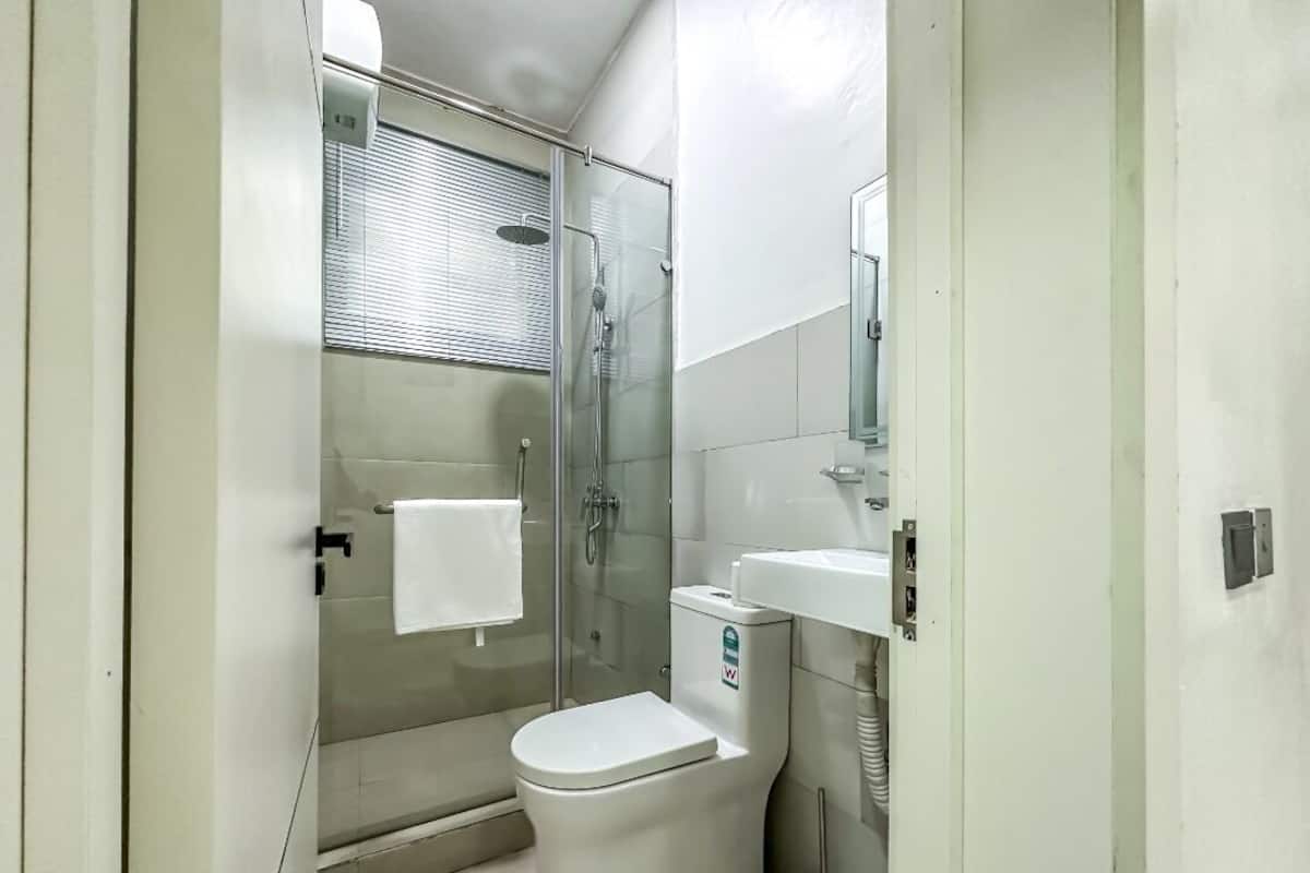 A small, modern bathroom with a glass-enclosed shower, a white toilet, and a sink with a mirror above it.