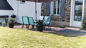 Une terrasse extérieure avec une table et des chaises, un barbecue et des plantes en pot.