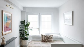 Una stanza con un letto, un termosifone, una pianta in vaso e quadri appesi alle pareti.