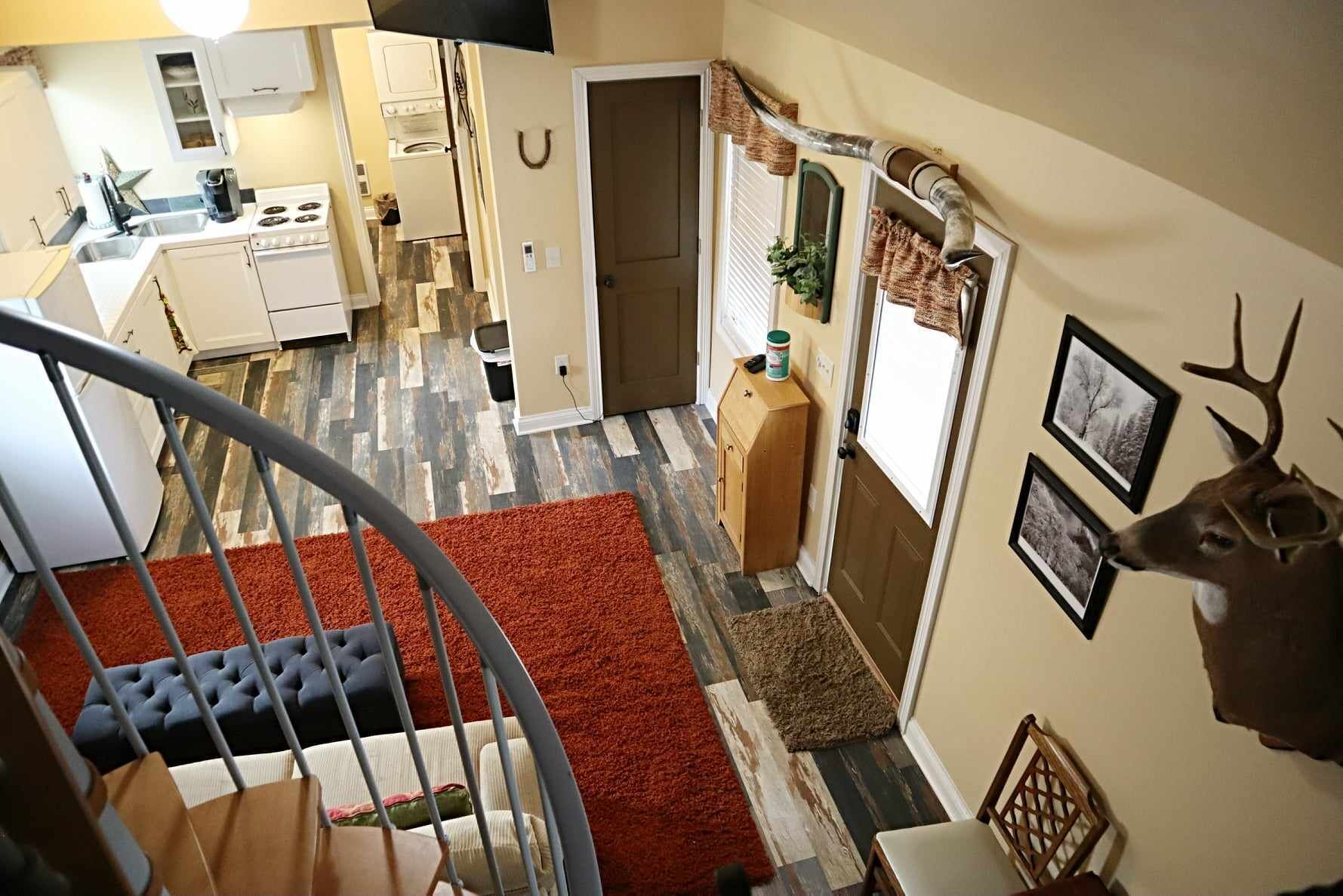 A staircase leading to a kitchen with white cabinets, a stove, and a sink.