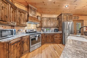 A kitchen with wooden cabinets, a stainless steel refrigerator, a microwave, and a stove.