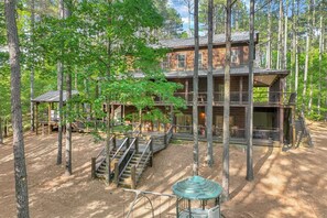 A multi-story cabin with a wooden exterior, surrounded by trees. - Low Rider Lodge backed up to Forest with ATV Trail Access from Driveway (Broken Bow)