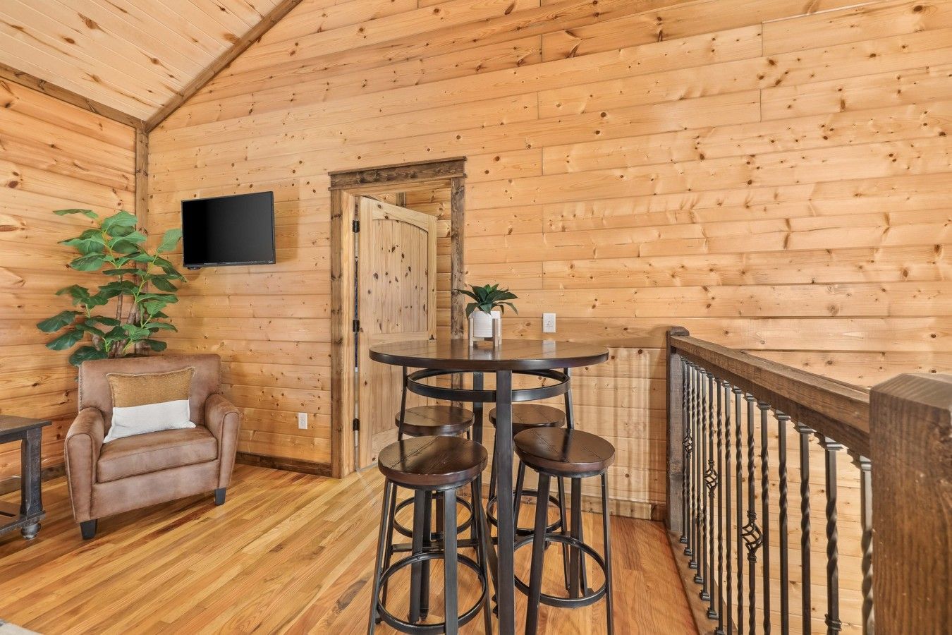 A wooden interior with a bar area, a chair, and a television mounted on the wall.