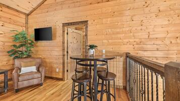 A wooden interior with a bar area, a chair, and a television mounted on the wall.