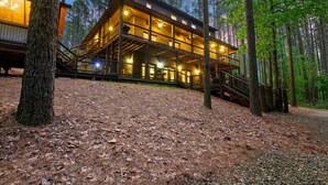 A multi-level wooden cabin with a staircase leading to the upper floor, surrounded by trees.