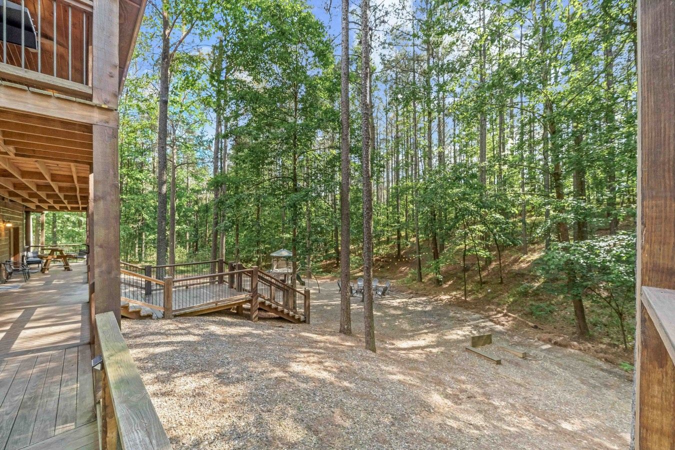 Une cabane en bois dotée d’une terrasse couverte et d’un espace salon extérieur, le tout entouré d’une forêt.