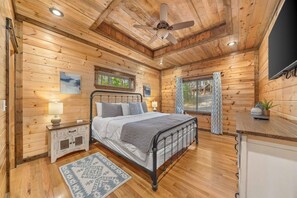 King bedroom with iron bed frame, nightstands, dresser and TV. - Low Rider Lodge backed up to Forest with ATV Trail Access from Driveway (Broken Bow)
