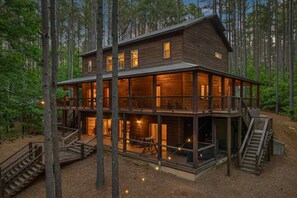 A multi-level wooden cabin with a balcony, surrounded by trees.
