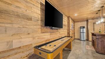 Un intérieur en bois avec un baby-foot, un téléviseur à écran plat et un réfrigérateur.