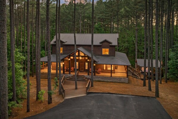 A cabin with a porch, a staircase, and a driveway.