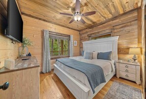 King bedroom with nightstands, dresser, TV and ceiling fan. - Low Rider Lodge backed up to Forest with ATV Trail Access from Driveway (Broken Bow)