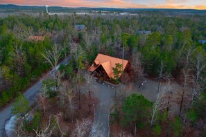 A cabin surrounded by dense forest with a clear road leading to it.